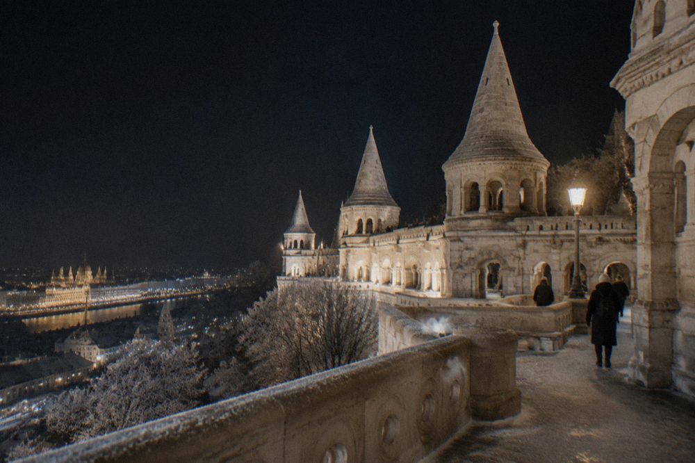 White towers and arches of the Fisherman's Bastion lit against a night sky