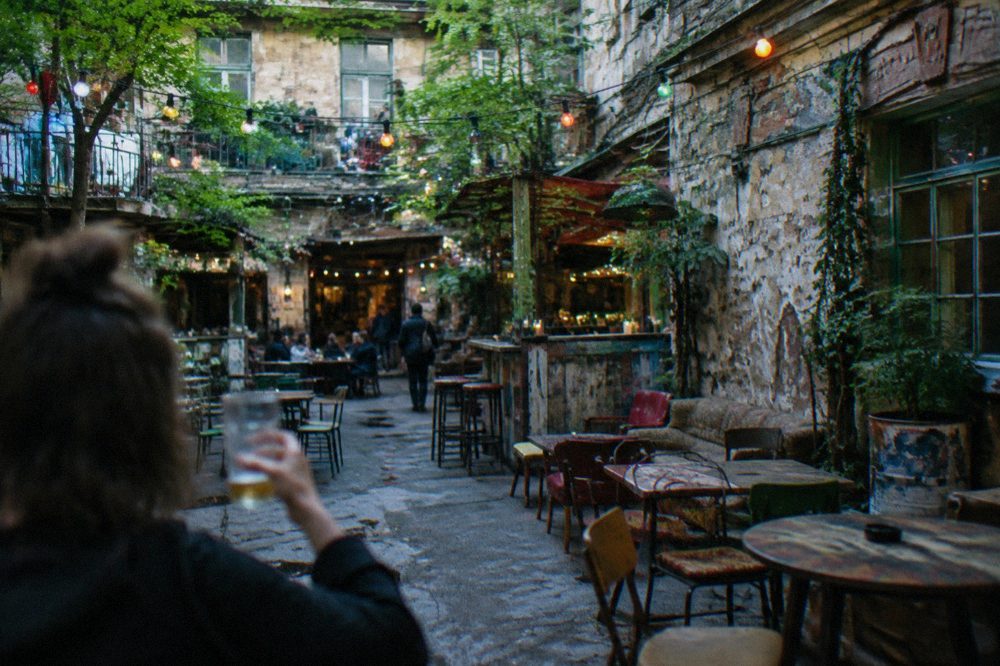 Courtyard of a Budapest ruin bar lit with coloured lights in the evening