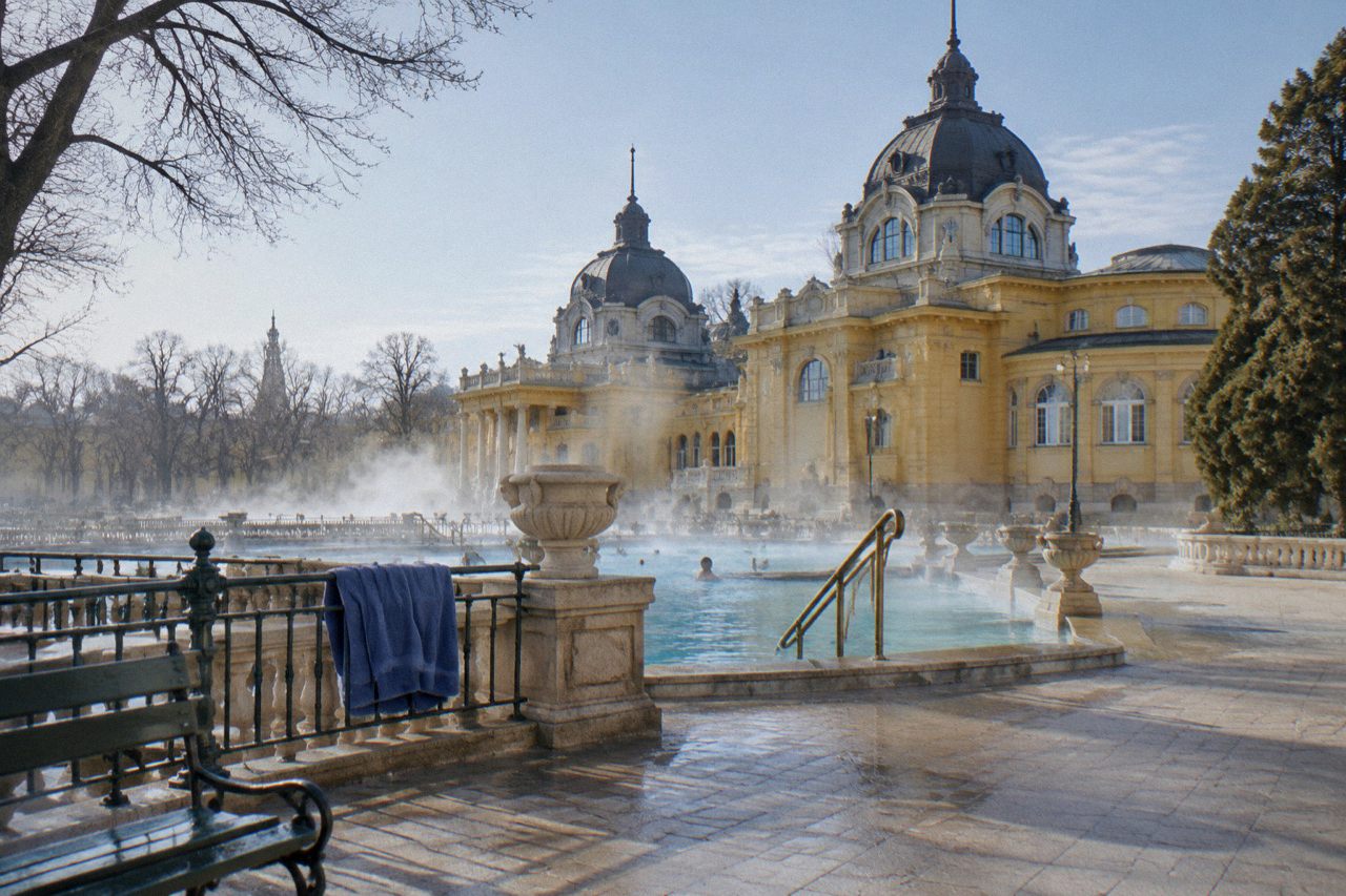 The yellow building and steaming outdoor pools of Szechenyi Baths in Budapest