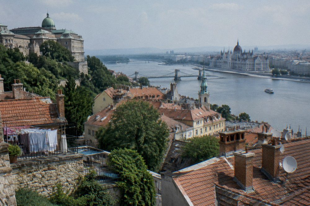 Wide view of Buda Castle Hill rooftops and the Danube from an upper terrace in Budapest