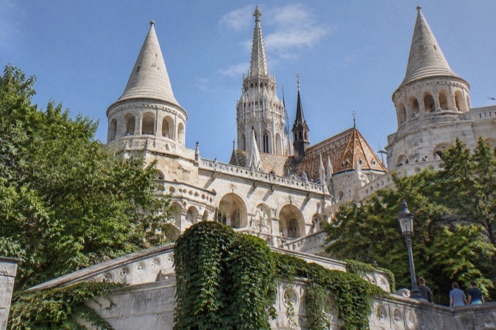 The lower terraces and white turrets of the Fisherman's Bastion seen from below, with the Matthias Church roof beyond.