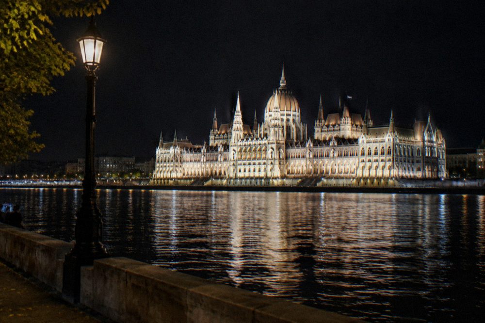 The illuminated Hungarian Parliament building seen from the Danube riverbank at night