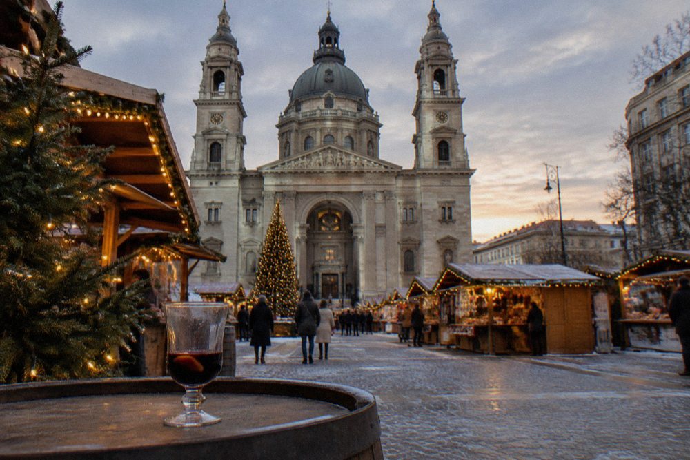 Festive wooden market stalls with string lights along a Budapest street in the evening