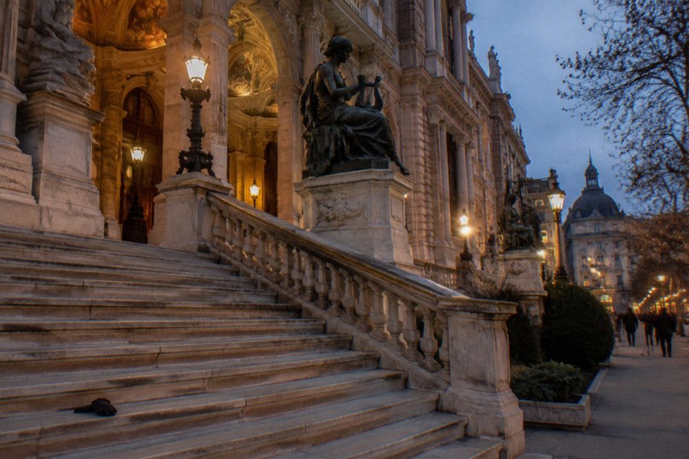 Grand museum staircase with columns and statuary under a high ceiling