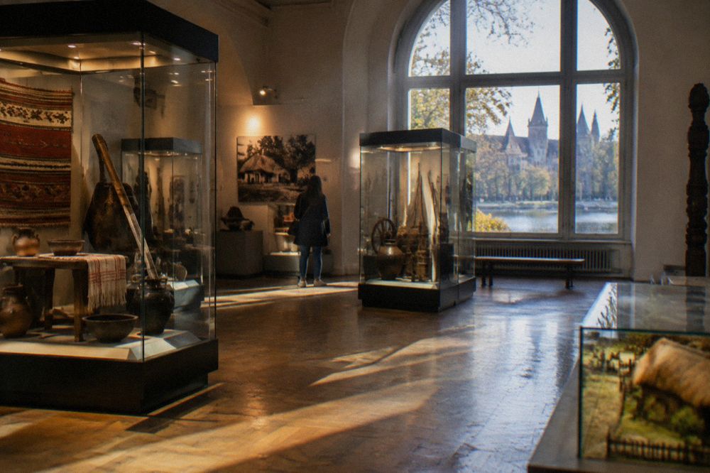 Museum exhibition hall with display cases and artefacts under warm lighting