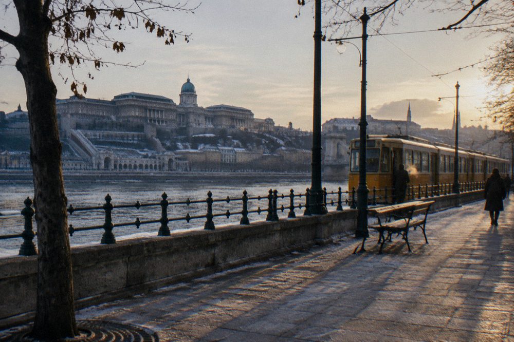 Yellow tram running along the Danube embankment with the castle hill behind