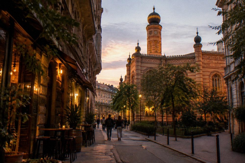 An evening street in the Jewish Quarter with lit bar signs and old facades