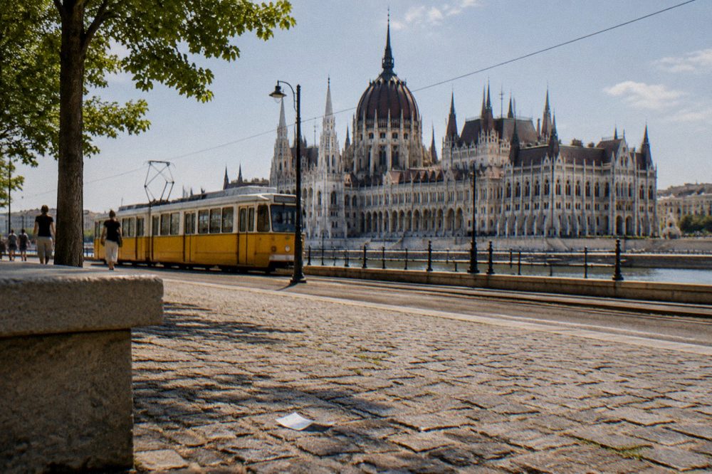 A yellow tram passing the Parliament building on the Danube embankment