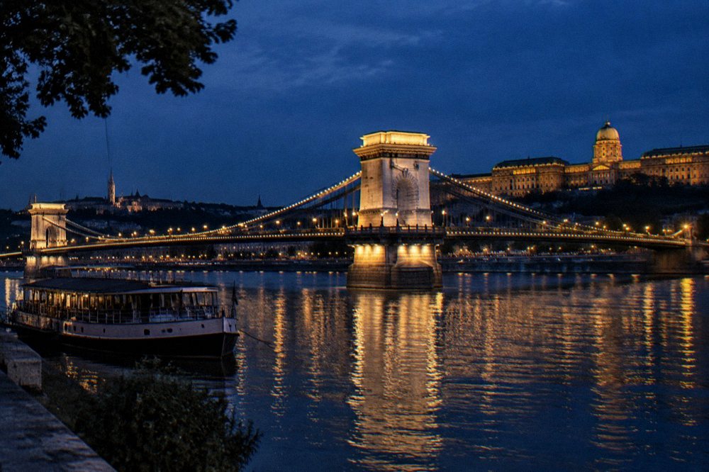 The Chain Bridge lit in the evening with the Danube reflecting the lights