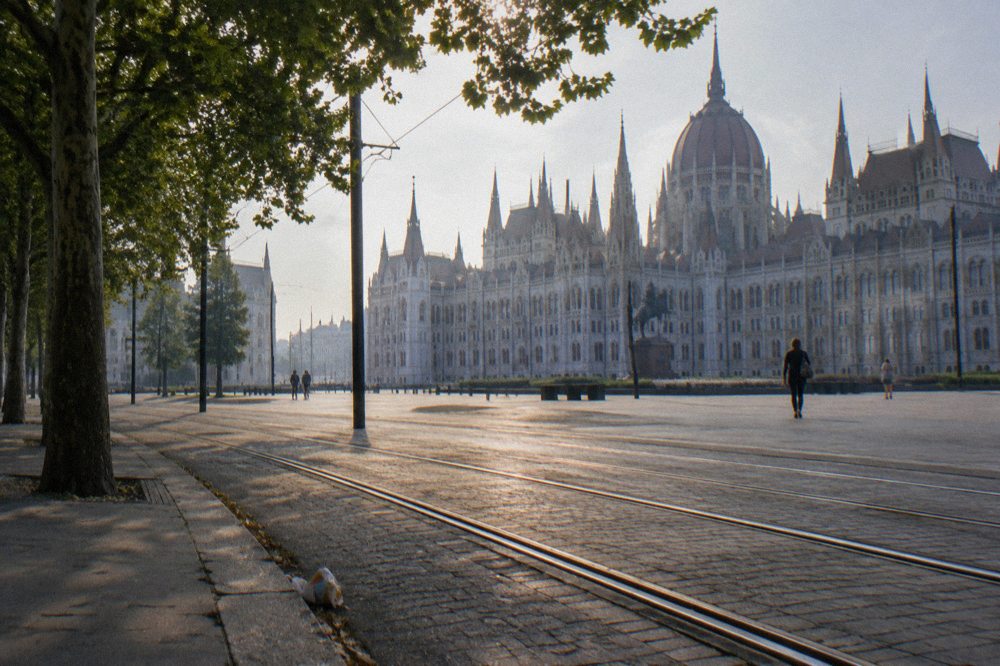 A wide Budapest square with grand facades and tram tracks in daylight