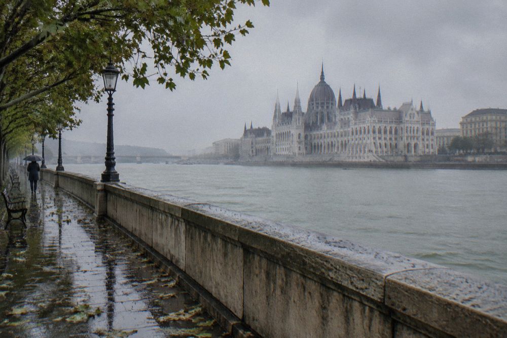 A riverside promenade in Budapest with the Parliament building across the water