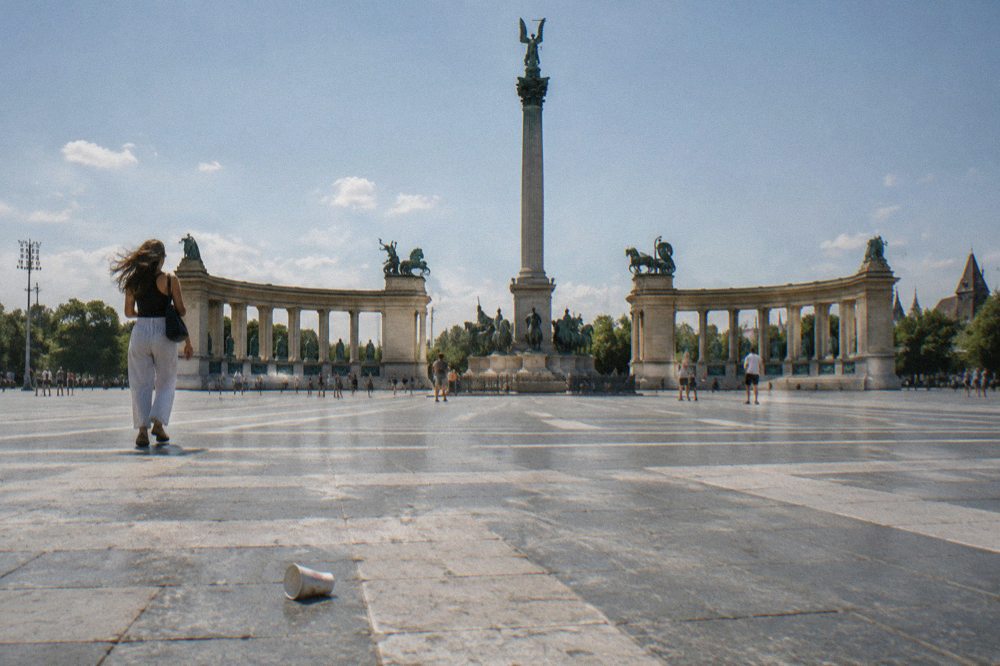 Open plaza of Heroes' Square in Budapest with a tall central column and a curved colonnade of statues