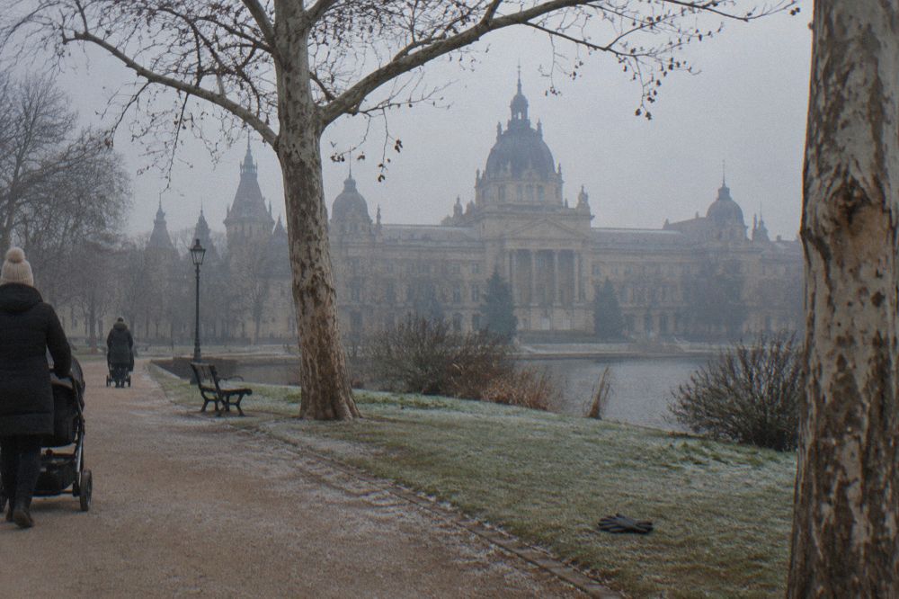 Museum building facade in Budapest seen from open park ground with trees and walkers in the foreground
